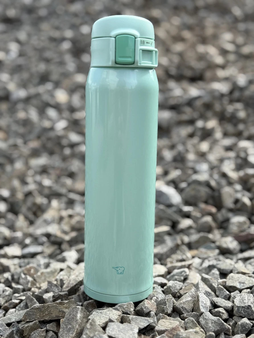 Zojirushi SM-SR60 Mint Travel Mug – 360 ml stainless steel insulated bottle with flip-top lid, BPA-free and reusable, photo on rocks.