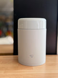 Light Blue thermos canister with a logo Zojirushi on a wooden surface