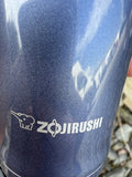 Zojirushi logo with elephant icon printed on a dark blue stainless steel thermal mug.