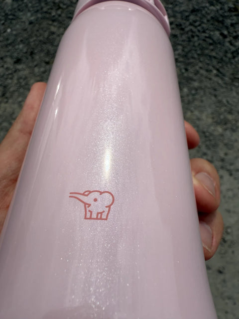 Close-up of Zojirushi logo on a pink stainless steel insulated travel mug, BPA-free design.